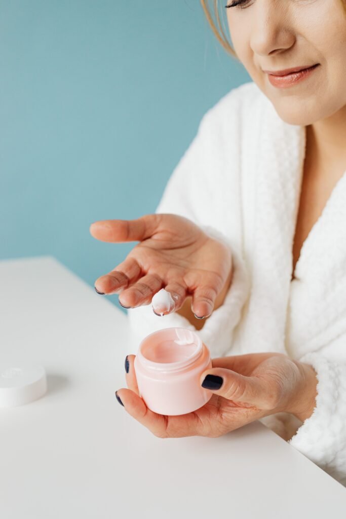 Close-up of a woman applying cream, emphasizing skincare routine and personal care.
