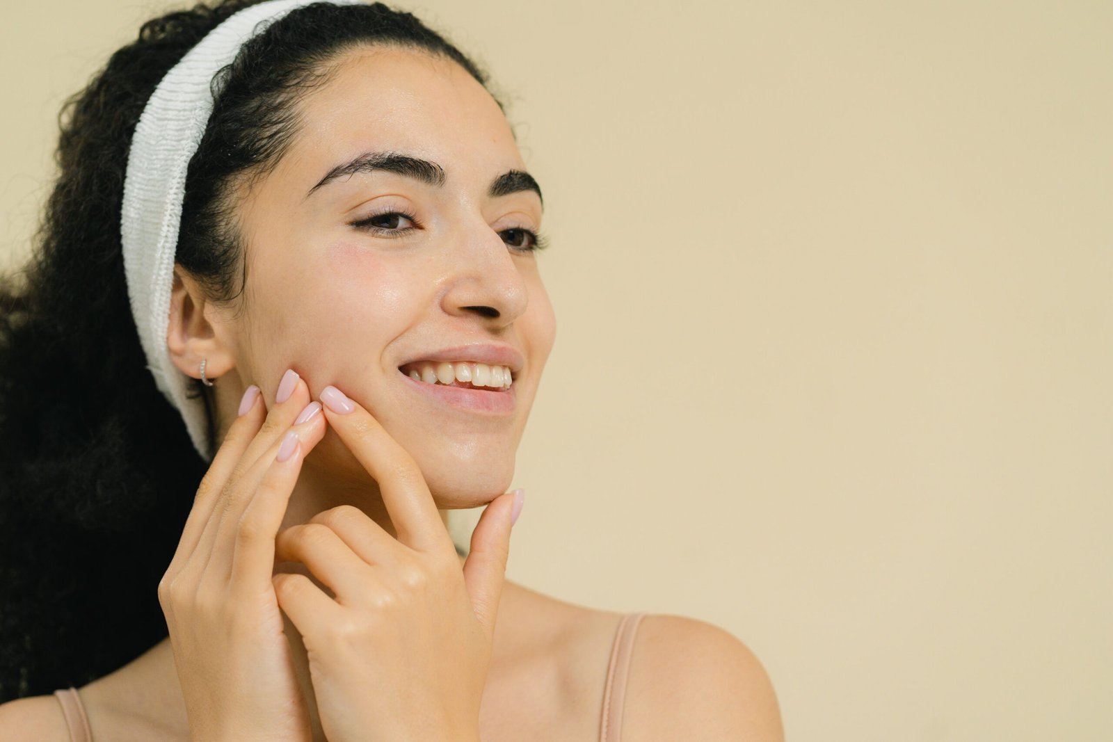 Close-up of a smiling woman applying skin treatment, promoting natural beauty and skincare.